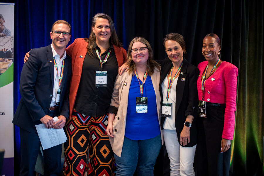 Jacq Brasseur of Ivy & Dean stands in the middle of the team from EY at CGLCC's 2023 2SLGBTQI+ Business Summit